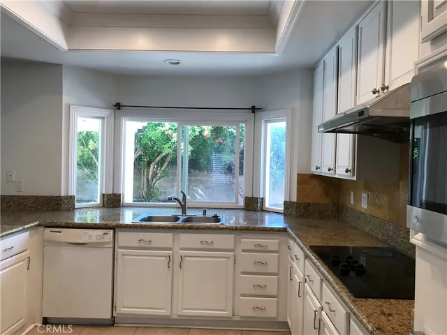a kitchen with granite countertop a sink and white cabinets