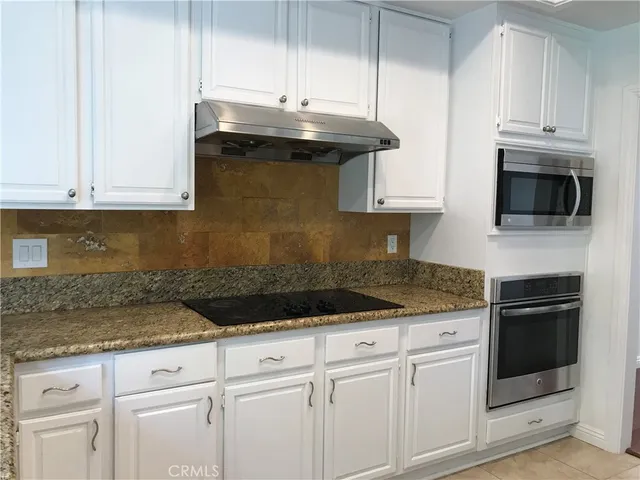 a kitchen with granite countertop white cabinets and a sink