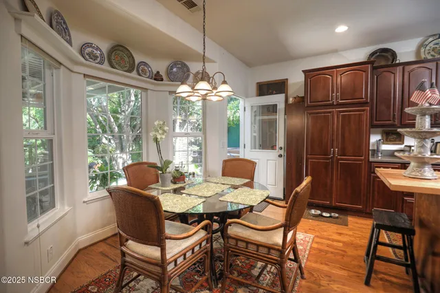 a kitchen with stainless steel appliances granite countertop a stove a refrigerator a sink dishwasher a dining table and chairs with wooden floor