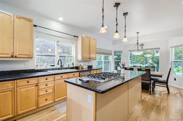 a kitchen with stainless steel appliances granite countertop a stove a sink dishwasher and white cabinets with wooden floor
