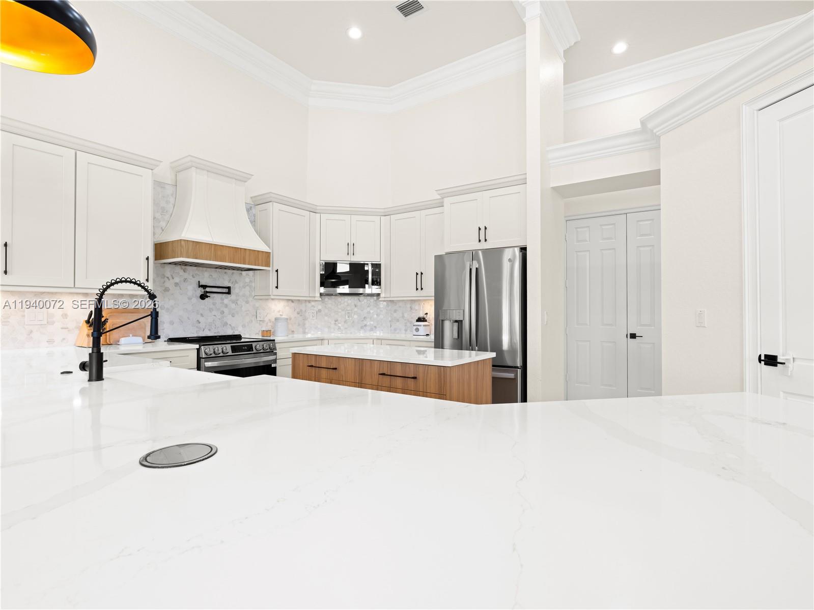 15016 Southwest 35th Street Davie, FL 33331 - Photo 13 of 50 a large white kitchen with kitchen island a sink stainless steel appliances and cabinets