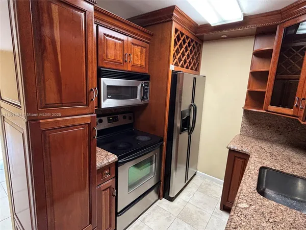 a kitchen with granite countertop stainless steel appliances a stove top oven and sink
