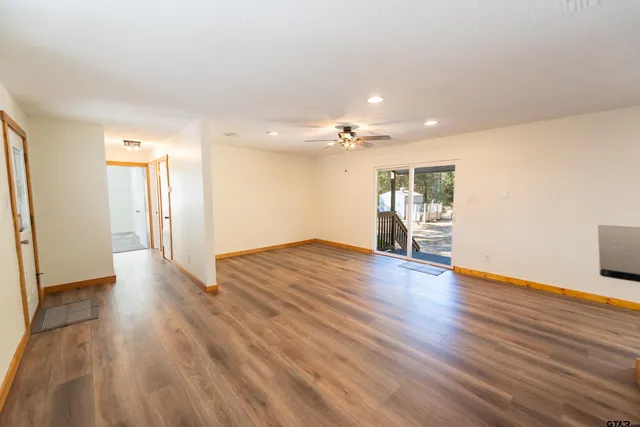 a view of a big room with wooden floor and a kitchen