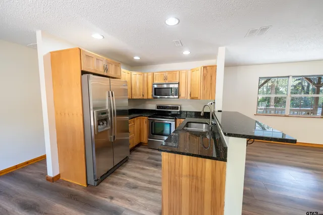 a kitchen with stainless steel appliances granite countertop a refrigerator a stove top oven a sink and dishwasher