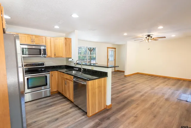 a kitchen with stainless steel appliances kitchen island granite countertop a stove a sink and a refrigerator