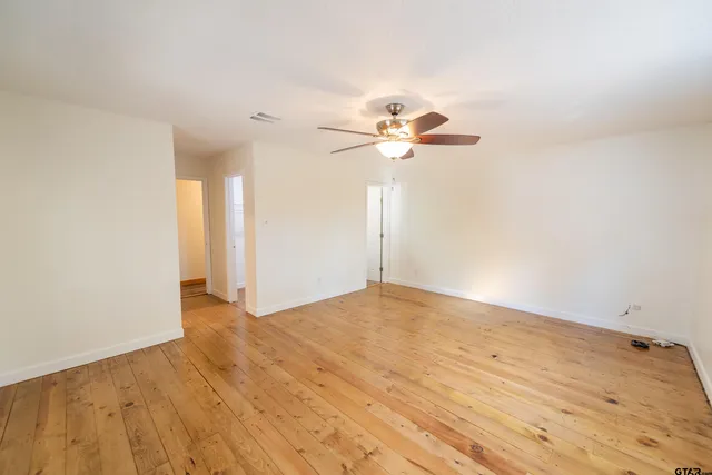 a view of an empty room with a chandelier fan