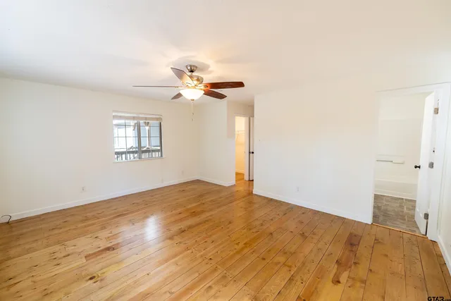 a view of an empty room with a chandelier fan and a window