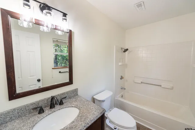 a bathroom with a granite countertop sink toilet mirror and shower