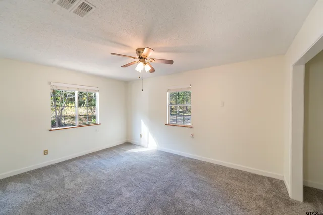 an empty room with windows and fan