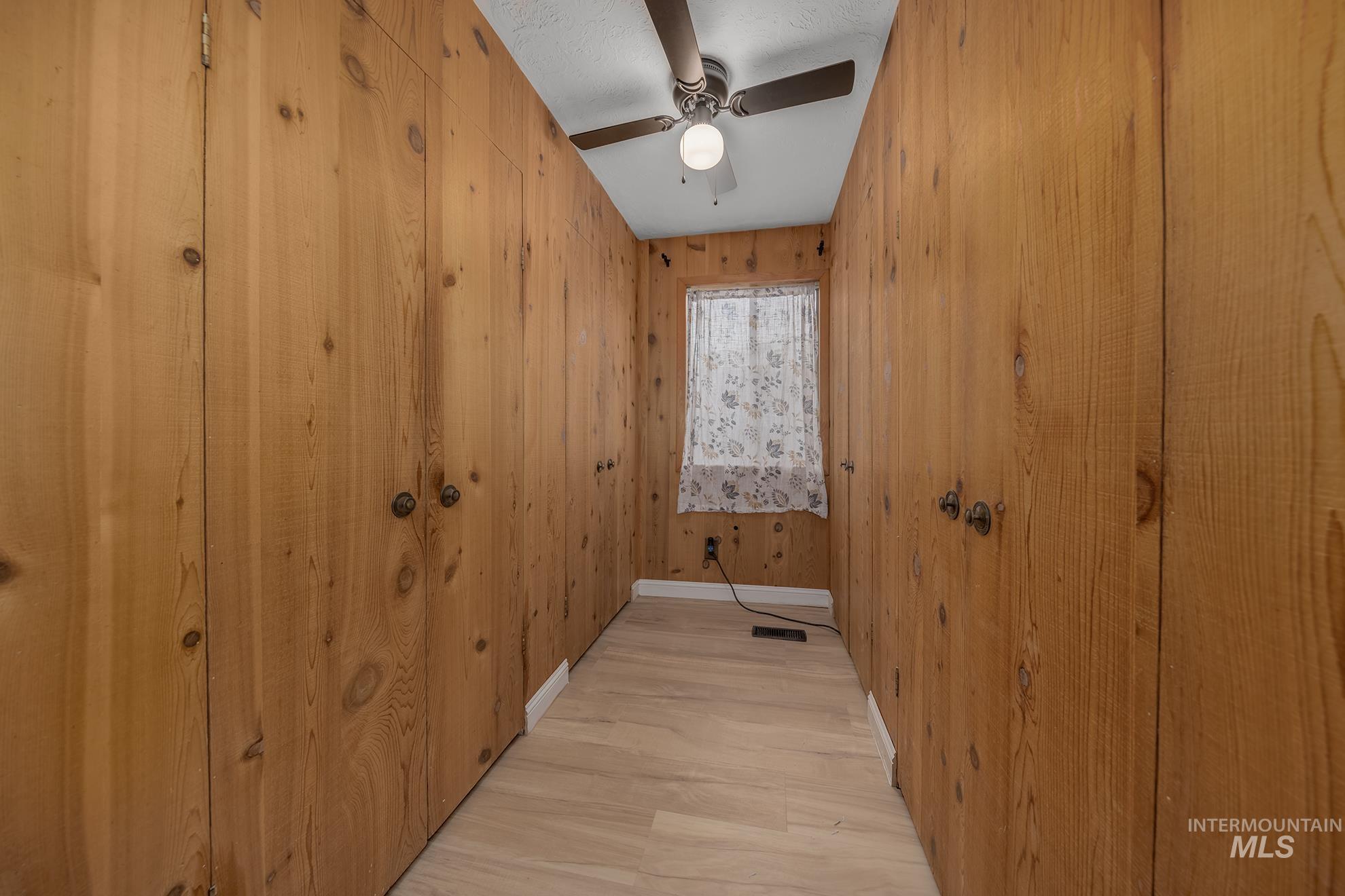 61 Southwest 4th Street Ontario, OR 97914 - Photo 14 of 42 Wood-paneled room featuring built-in storage, light wood-finish flooring, a window, and a ceiling fan with integrated lighting
