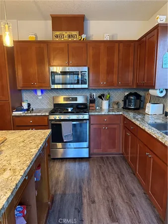 a kitchen with stainless steel appliances granite countertop wooden cabinets a stove and a sink