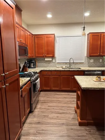 a kitchen with stainless steel appliances granite countertop a sink a stove and a refrigerator