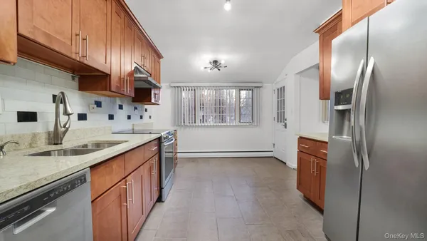 a kitchen with stainless steel appliances granite countertop a refrigerator a sink dishwasher a stove and a dining table with wooden floor