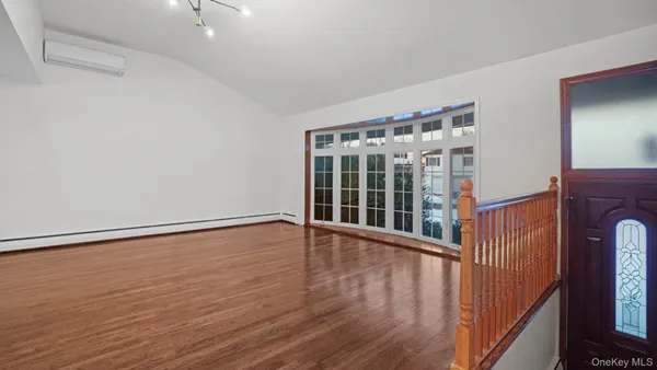 a view of an empty room with wooden floor and fan