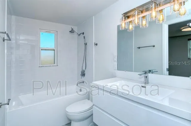 a bathroom with a granite countertop sink a toilet and a large mirror