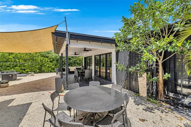 a patio with a table and chairs and potted plants