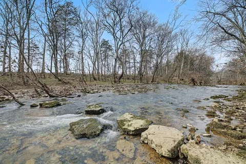 a backyard of a house with large trees and wooden fence