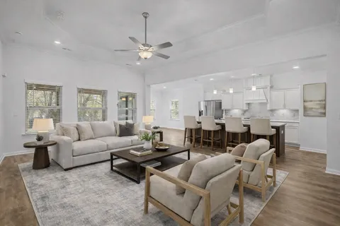 a living room with furniture kitchen view and a chandelier