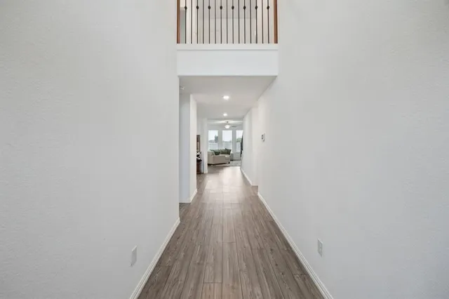 a view of a hallway with wooden floor and a bathroom