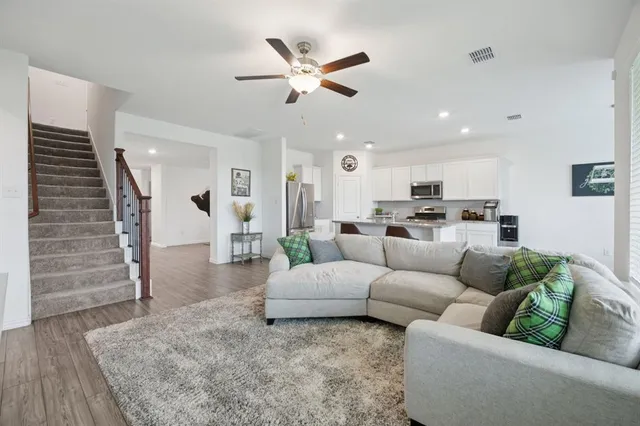 a living room with furniture kitchen view and a wooden floor