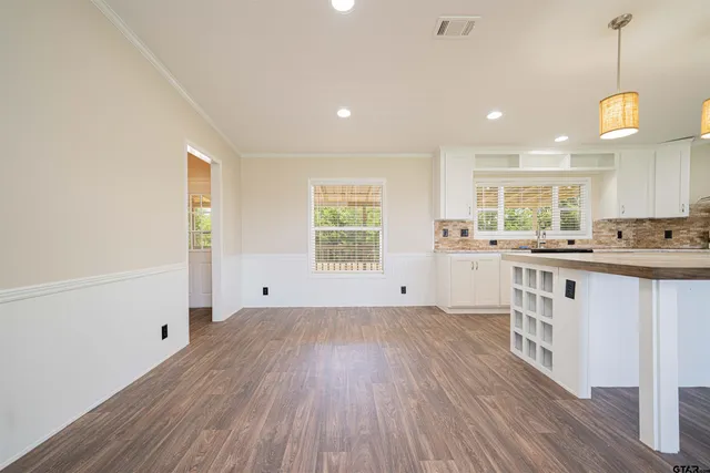 a large kitchen with granite countertop a sink white cabinets and stainless steel appliances