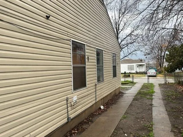 a view of a white house with a small yard and large tree