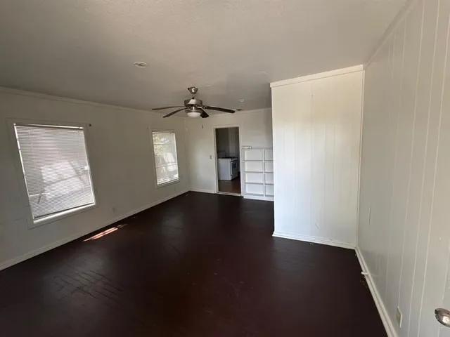 an empty room with wooden floor cabinet and windows