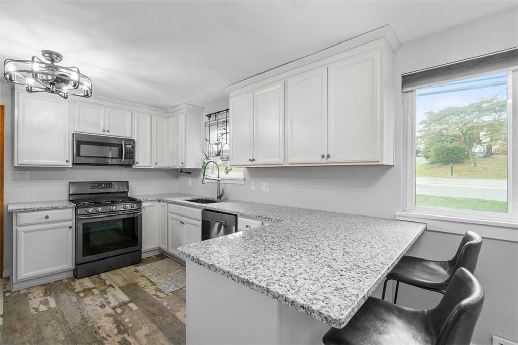 217 McMichael Road Carnegie, PA 15106 - Photo 12 of 38 a kitchen with stainless steel appliances granite countertop a stove top oven a sink dishwasher and a refrigerator with wooden floor
