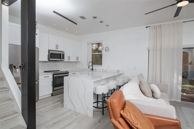 a kitchen with stainless steel appliances granite countertop a refrigerator a stove a sink dishwasher and microwave with wooden floor