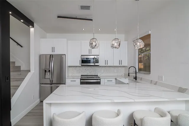 a kitchen with stainless steel appliances granite countertop a sink a stove and a refrigerator