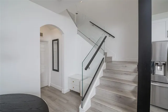 a living room with stainless steel appliances furniture a clock and a view of kitchen
