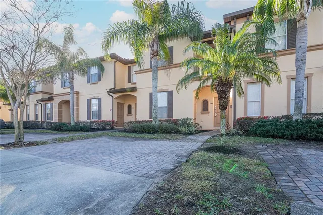 a view of a white house with a yard and palm trees