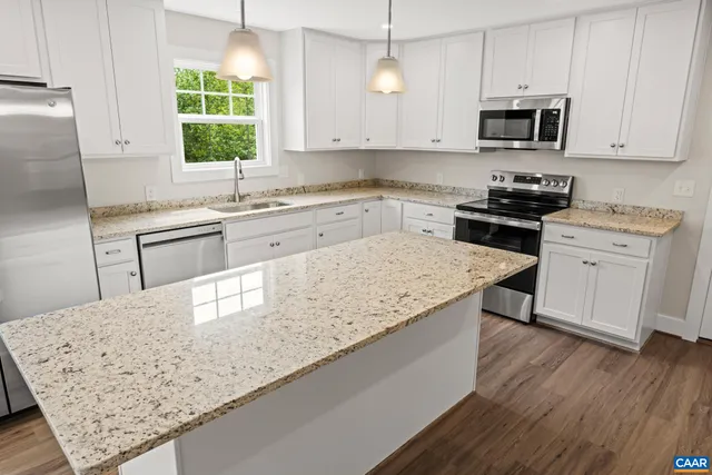 a kitchen with granite countertop a sink stainless steel appliances and white cabinets