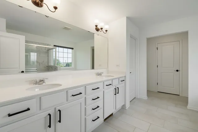 a spacious bathroom with double sink and a mirror