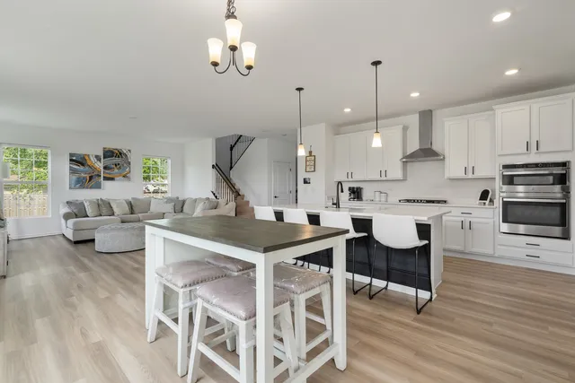 a kitchen with stainless steel appliances kitchen island granite countertop a table chairs and a refrigerator