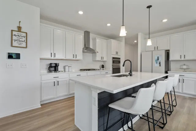 a kitchen with white cabinets appliances and chairs