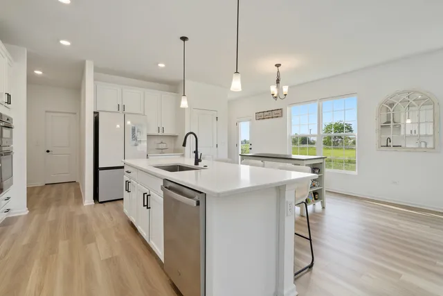 a kitchen with stainless steel appliances a sink a stove a refrigerator cabinets and a wooden floor