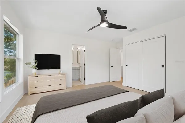 a bedroom with a bed a flat screen tv and a window
