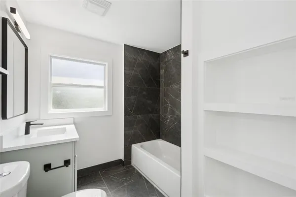 a bathroom with a bathtub a sink a toilet and a window