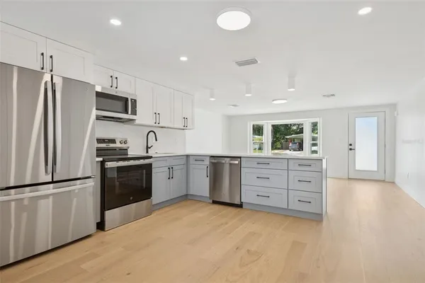 a kitchen with granite countertop a refrigerator stove top oven and sink