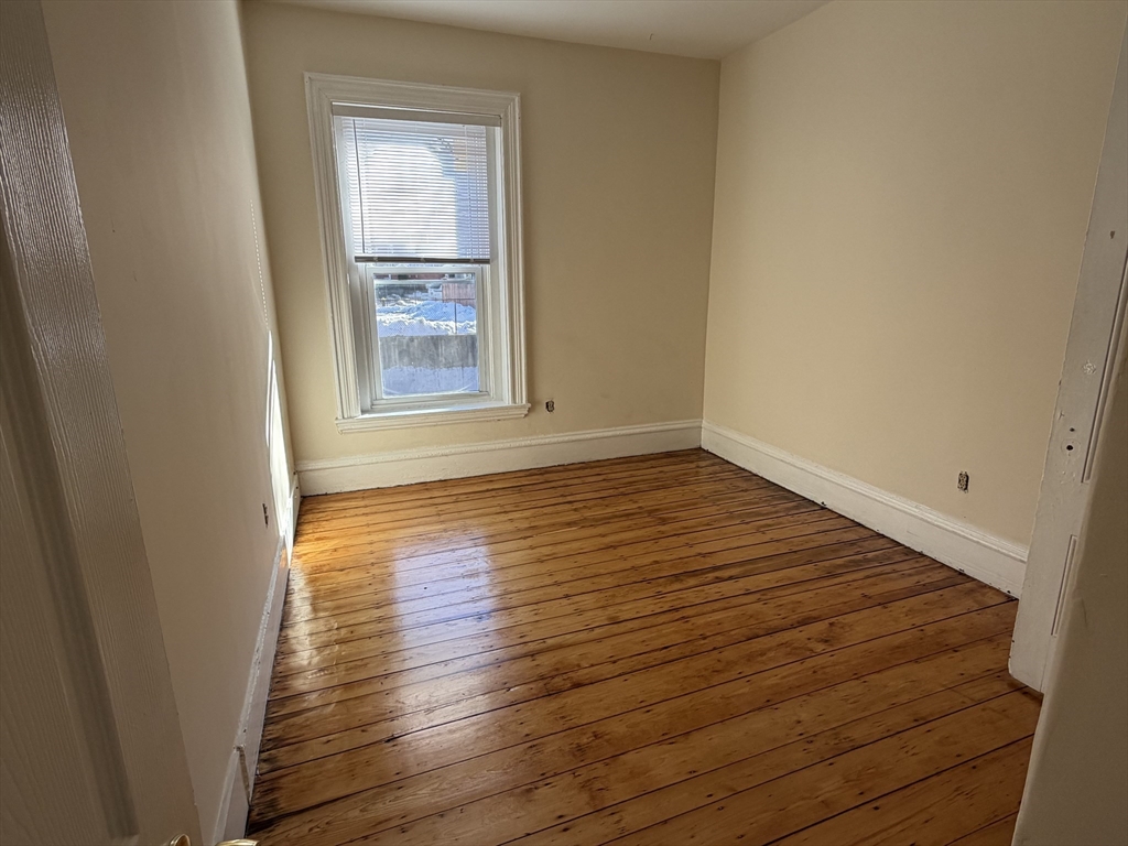 227 Roxbury Street, Unit 4 Boston, MA 02119 - Photo 4 of 7 a view of an empty room with wooden floor and a window