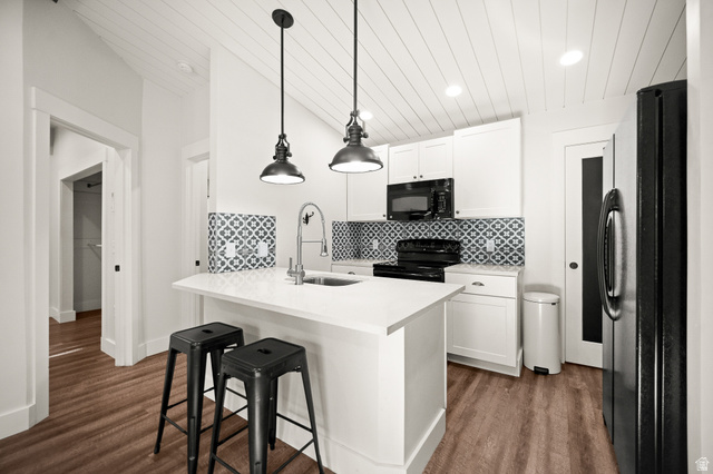 236 West 300 South Hurricane, UT 84737 - Photo 46 of 76 Kitchen featuring a central island with white countertop, white cabinetry, decorative tile backsplash, black appliances, and wood-finish flooring