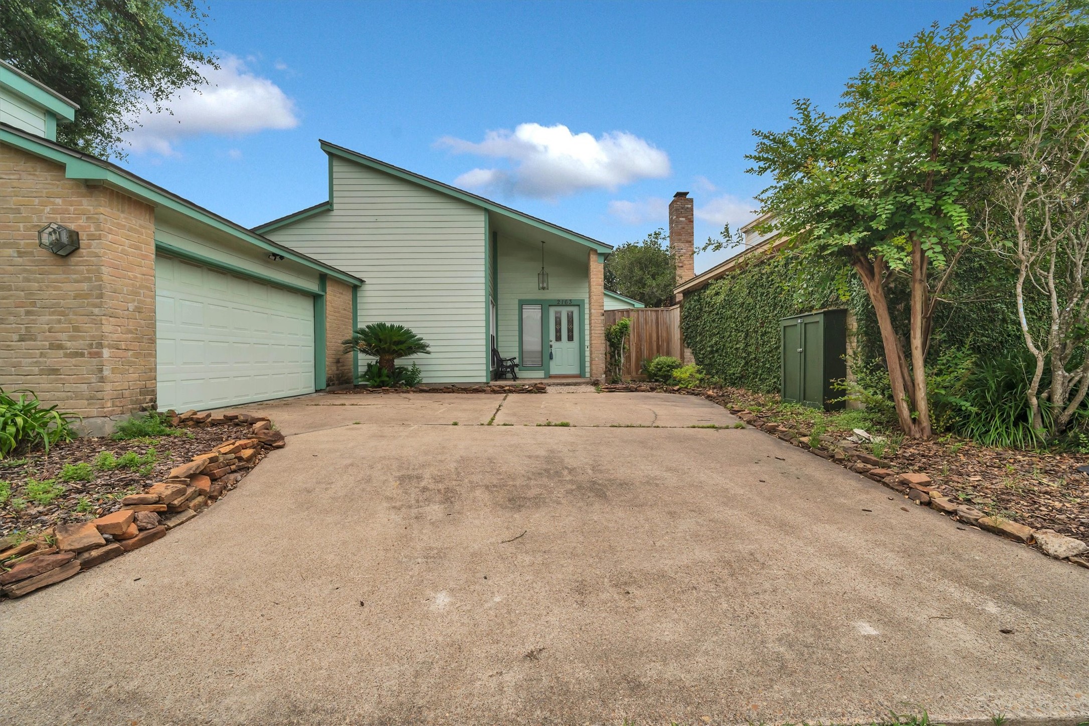 2163 Paso Rello Drive Houston, TX 77077 - Photo 2 of 45 The entrance is accented with a covered porch and a glass-paneled door, creating a welcoming appearance.