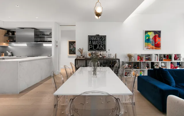 a living room with stainless steel appliances furniture a rug and a kitchen view