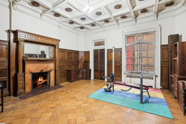 a view of a hall with wooden floor and a fireplace