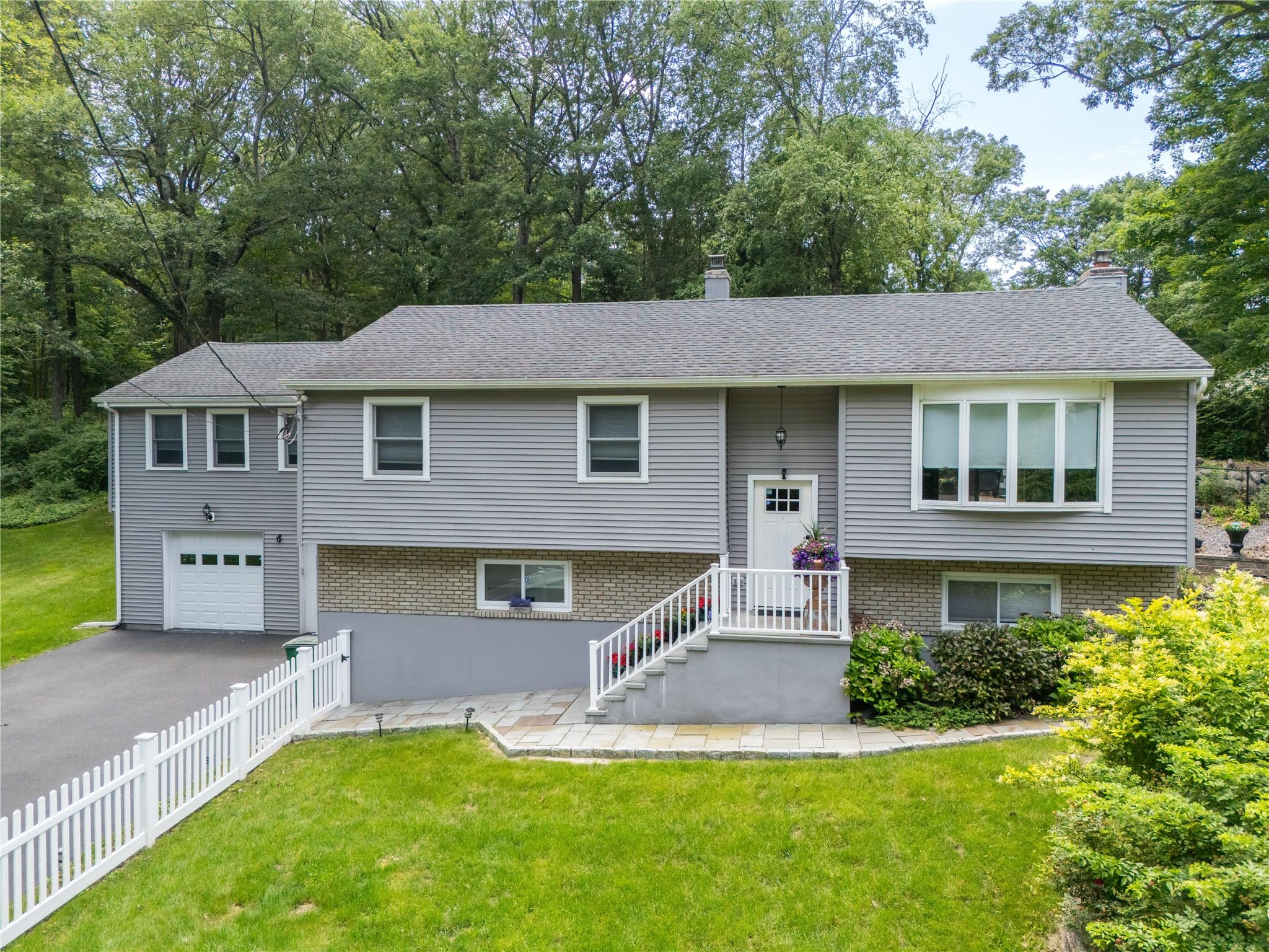 581 Wood Road Mahopac, NY 10541 - Photo 1 of 1 Bi-level home with a chimney, an attached garage, brick siding, and driveway