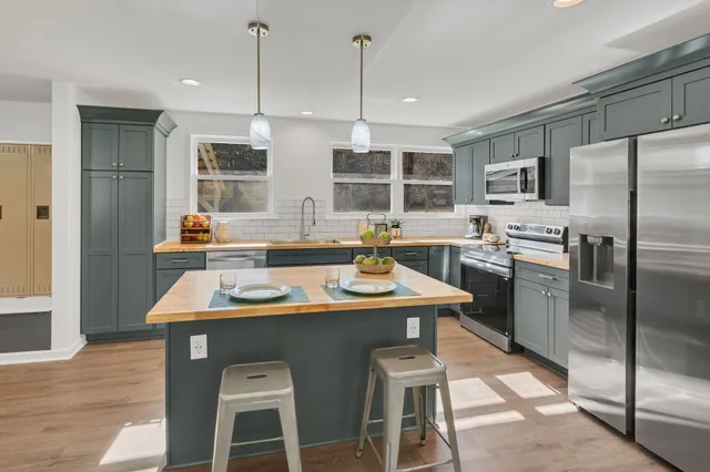 a kitchen with stainless steel appliances granite countertop a sink a stove and a refrigerator