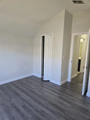 an empty room with wooden floor & closet area