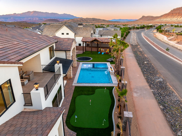 4871 South Homestead Way Washington, UT 84780 - Photo 132 of 151 Pool at dusk with a patio, a mountain view, an area to practice putting, and a pergola