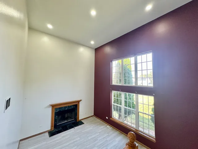 an empty room with windows and fireplace